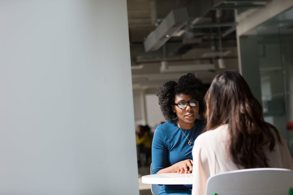 Two women engaged in a discussion in a modern office environment